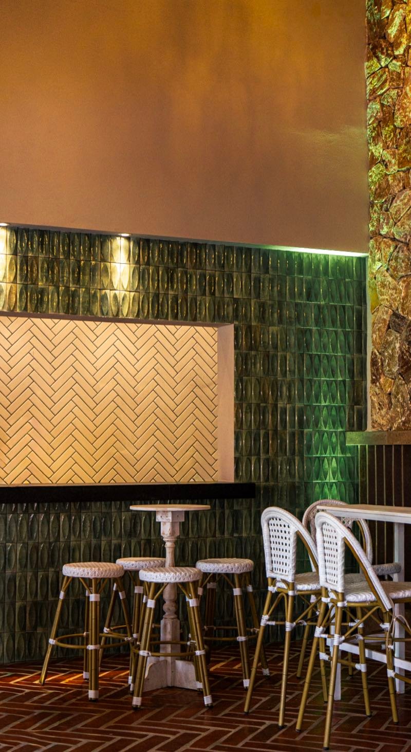 Muro de azulejos artesanales verdes con bancos altos